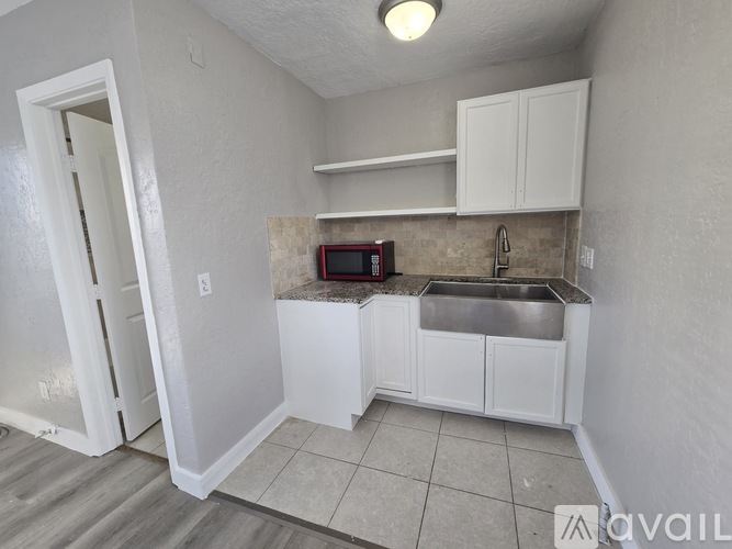 A small kitchen with white cabinets and a microwave.