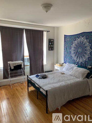 A bedroom with a bed, a chair, and a window with curtains.