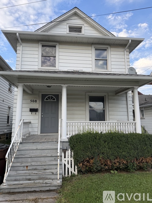 A two-story house with a front porch and a white picket fence.