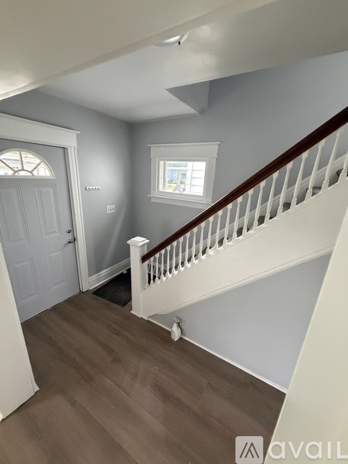 A hallway with a wooden floor and white railings.