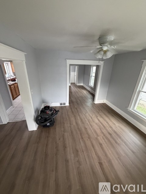 A room with a ceiling fan and wooden flooring.