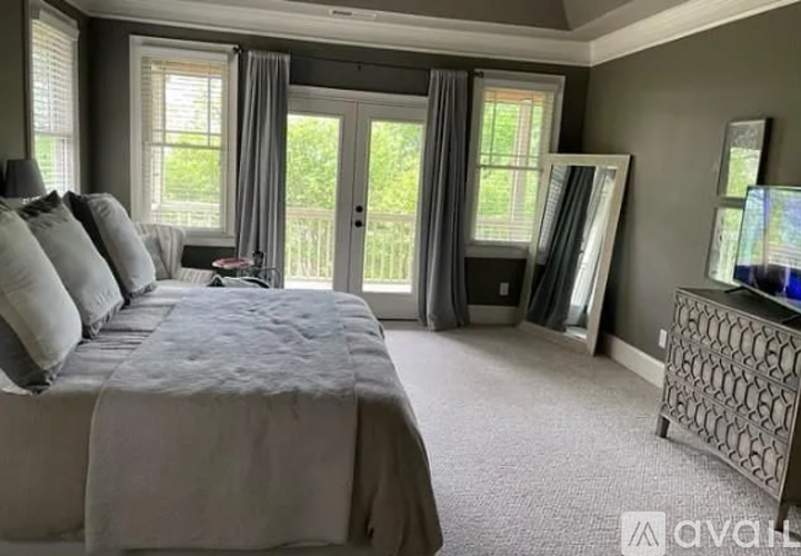 A bedroom with a large bed and a balcony with a door.