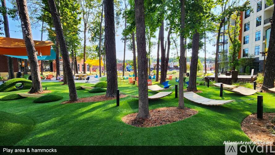 A play area with hammocks and a playground in the background.