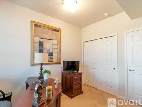 A room with a wooden table, a television, a lamp, and a painting on the wall.