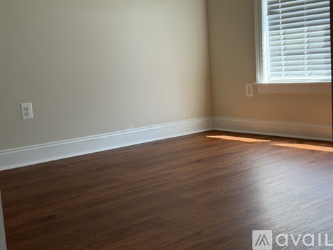 A room with wooden flooring and a window with blinds.