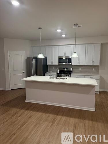 A kitchen with white cabinets and a white island with a sink.