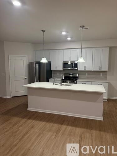 A kitchen with white cabinets and a white island with a sink.
