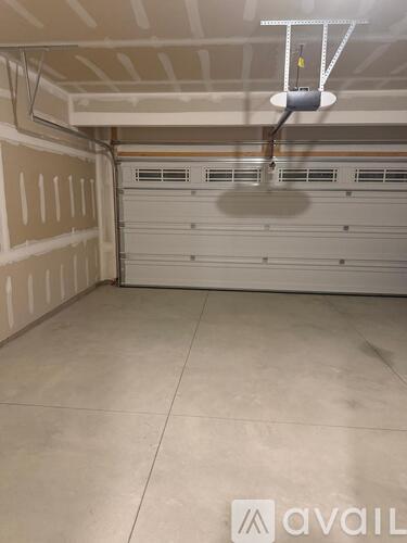 A spacious garage with a closed white door and a hanging light fixture.