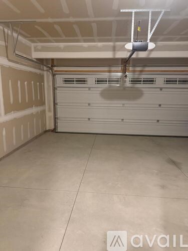 A spacious garage with a closed white door and a hanging light fixture.