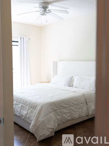 A bedroom with a white bed and a ceiling fan.