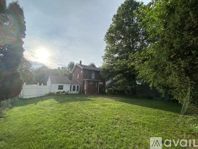 A house is surrounded by a green lawn and trees.