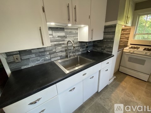 A kitchen with white cabinets and a black countertop.