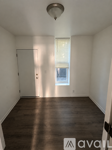 A room with wooden floors and a window with blinds.