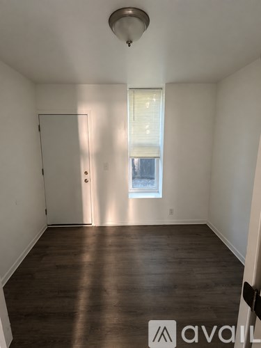 A room with wooden floors and a window with blinds.