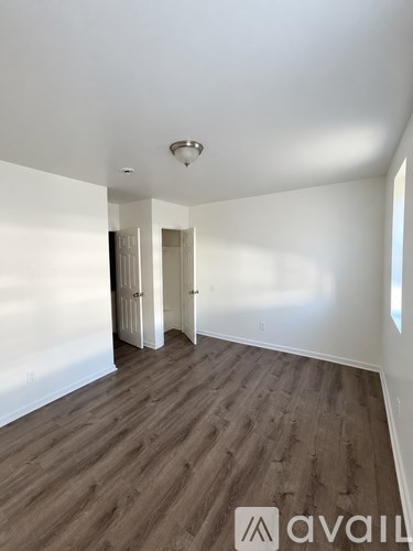 A room with wooden flooring and white walls, with a light on the ceiling and a logo on the floor.