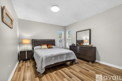 A bedroom with a bed, nightstand, and a dresser with a mirror.