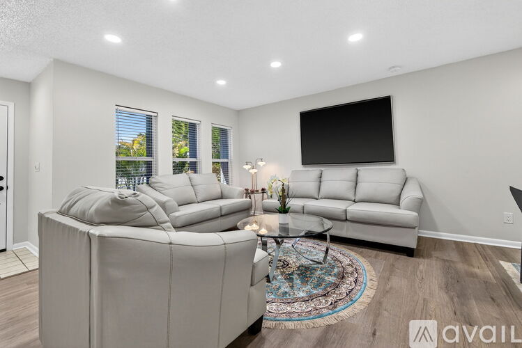 A modern living room with a large grey sofa and a flat screen TV mounted on the wall.