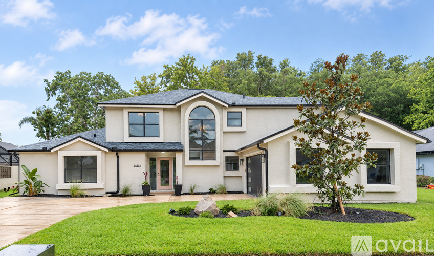 A large, two-story house with a front yard and a tree.