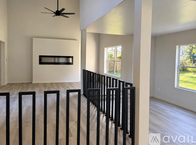 A spacious living room with a row of black metal railings on the left side.
