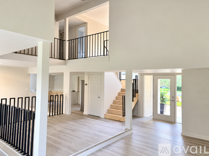 A spacious interior of a modern home with a staircase and balcony.