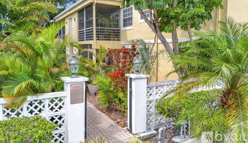 A white fence with a plaque on it is in front of a building.