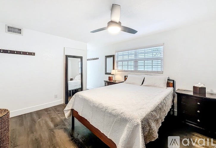 A bedroom with a bed, dresser, and window with blinds.
