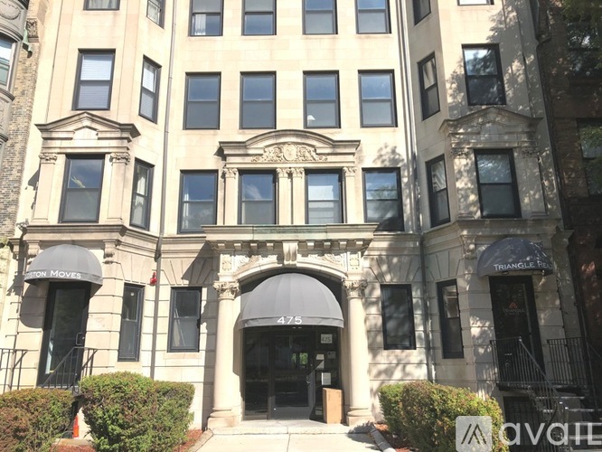 A building with a large arched entrance and awnings on the windows.