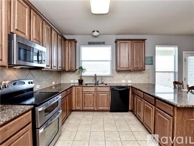 A kitchen with brown cabinets and black appliances.