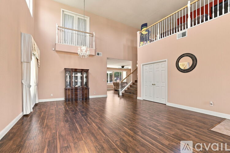 A spacious room with wood flooring and a staircase with a railing.