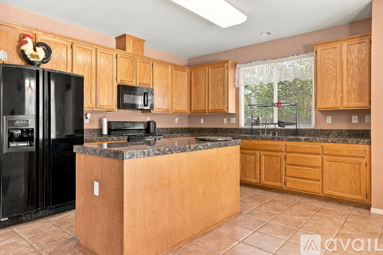 A kitchen with wooden cabinets and a black refrigerator.