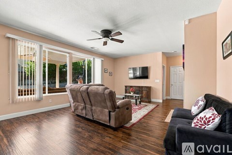 A living room with a brown couch and a ceiling fan.