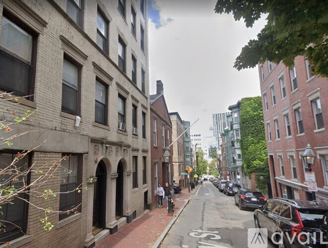 A street view of a city with buildings on both sides and cars parked on the side of the road.
