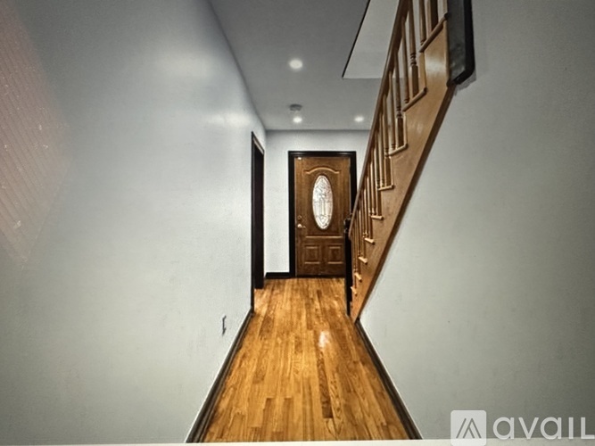 A hallway with a wooden floor and a door at the end.