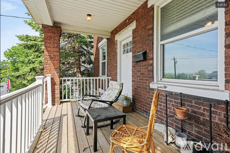 A balcony with a black chair and a wicker chair.