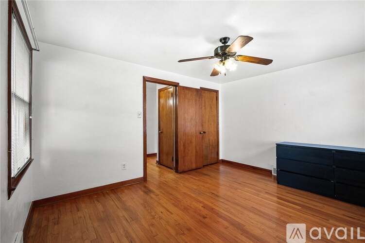 A room with a ceiling fan and wooden floors.