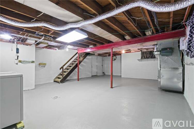 A large empty room with a staircase and a red pole.
