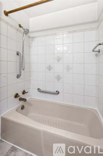 A white tiled bathroom with a beige tub and a gold shower rod.