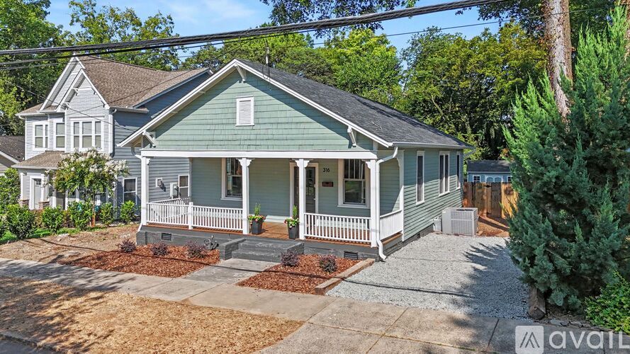 A house with a green roof and white porch is for sale.