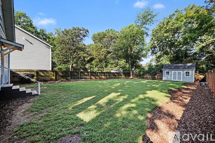 A backyard with a shed, a small house, and a lawn.