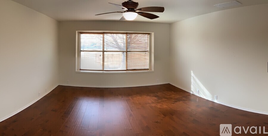 A room with a ceiling fan and a window with blinds.