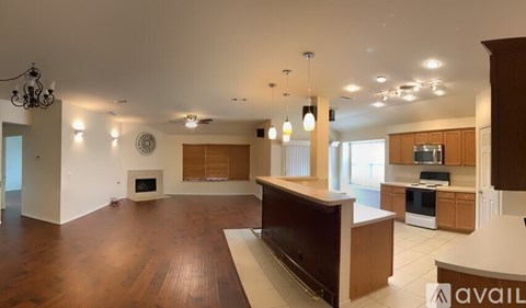 A spacious living room with a fireplace and a kitchen area with wooden cabinets.
