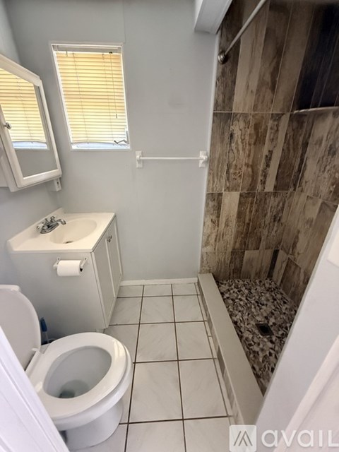 A bathroom with a toilet, sink, and tiled floor.