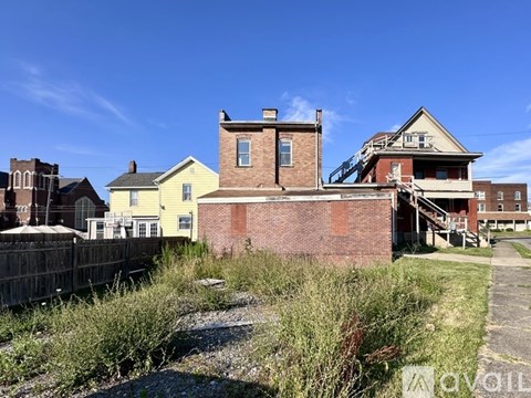 A yellow house is in front of a red brick building.