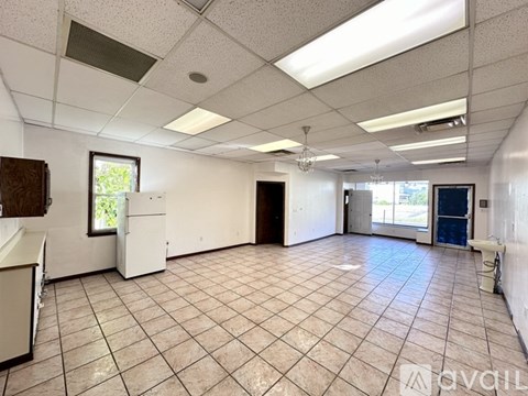 A spacious room with tile flooring and a mix of white and dark furnishings.