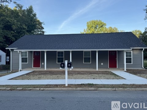 A two-story house with a grey exterior and red doors is for sale.