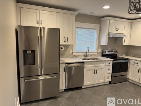 A modern kitchen with a stainless steel refrigerator and white cabinets.