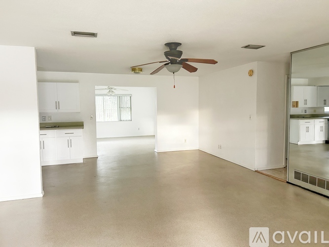 A spacious room with a ceiling fan and a mirror on the wall.