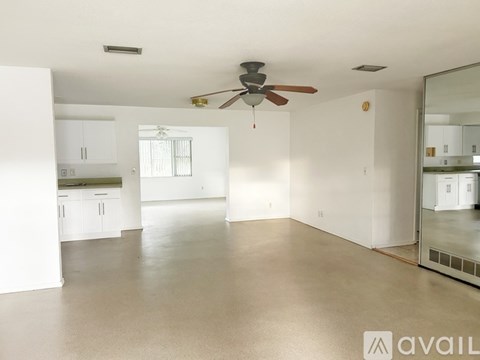 A spacious room with a ceiling fan and a mirror on the wall.
