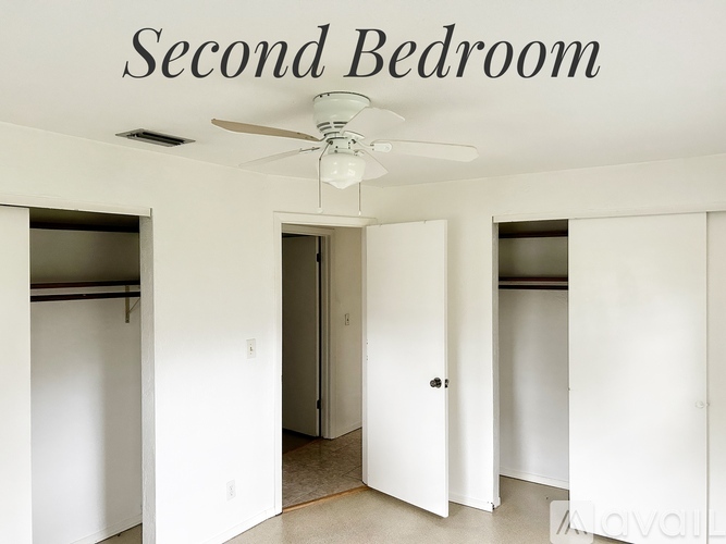 A second bedroom with a ceiling fan and white walls.