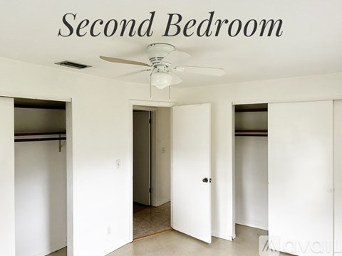 A second bedroom with a ceiling fan and white walls.